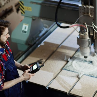 trabalhador-de-fabrica-operando-maquina-industrial-e-configurando-parametros-no-computador.